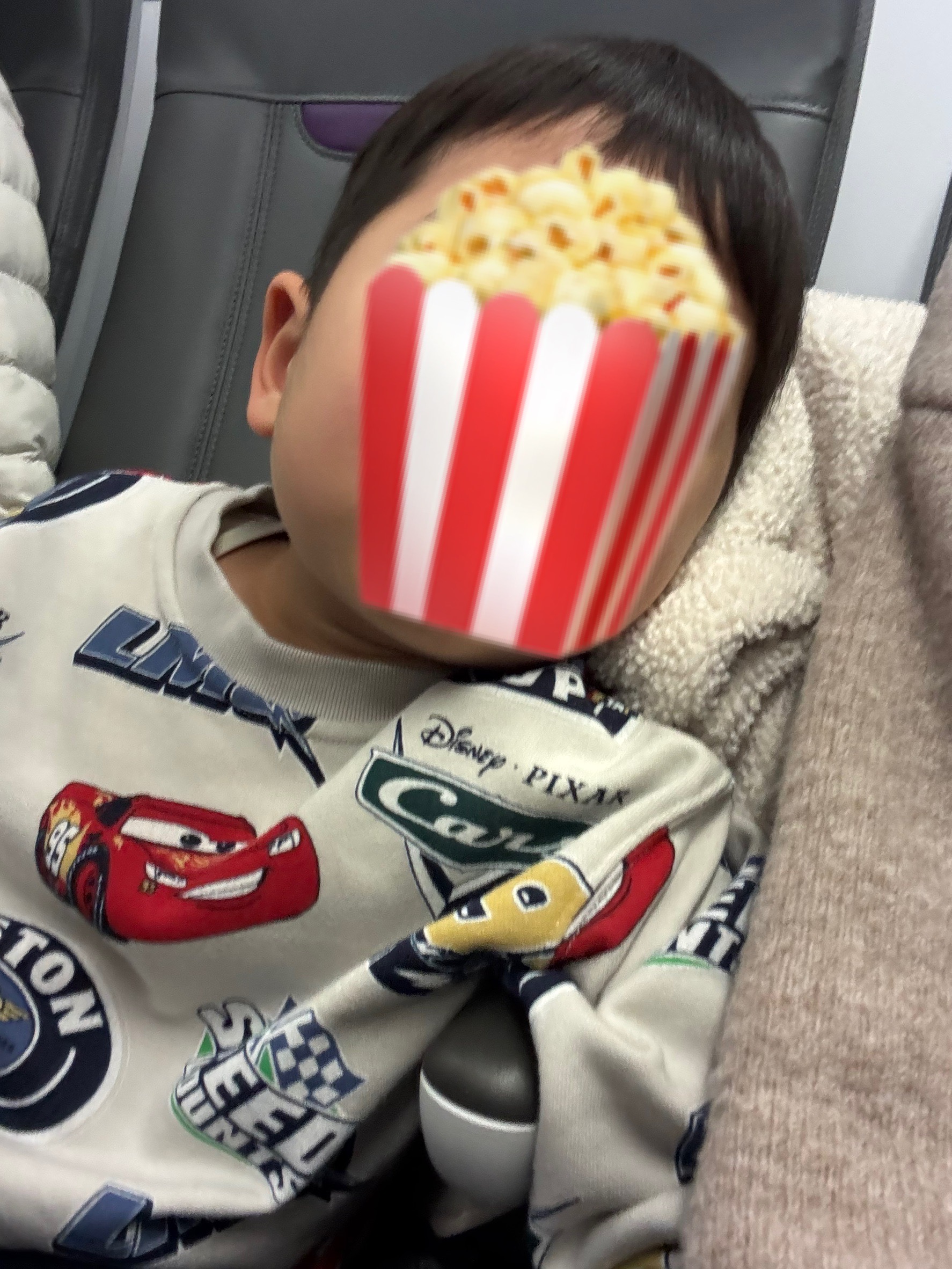 飛行機で上着をクッションがわりにして眠る子ども