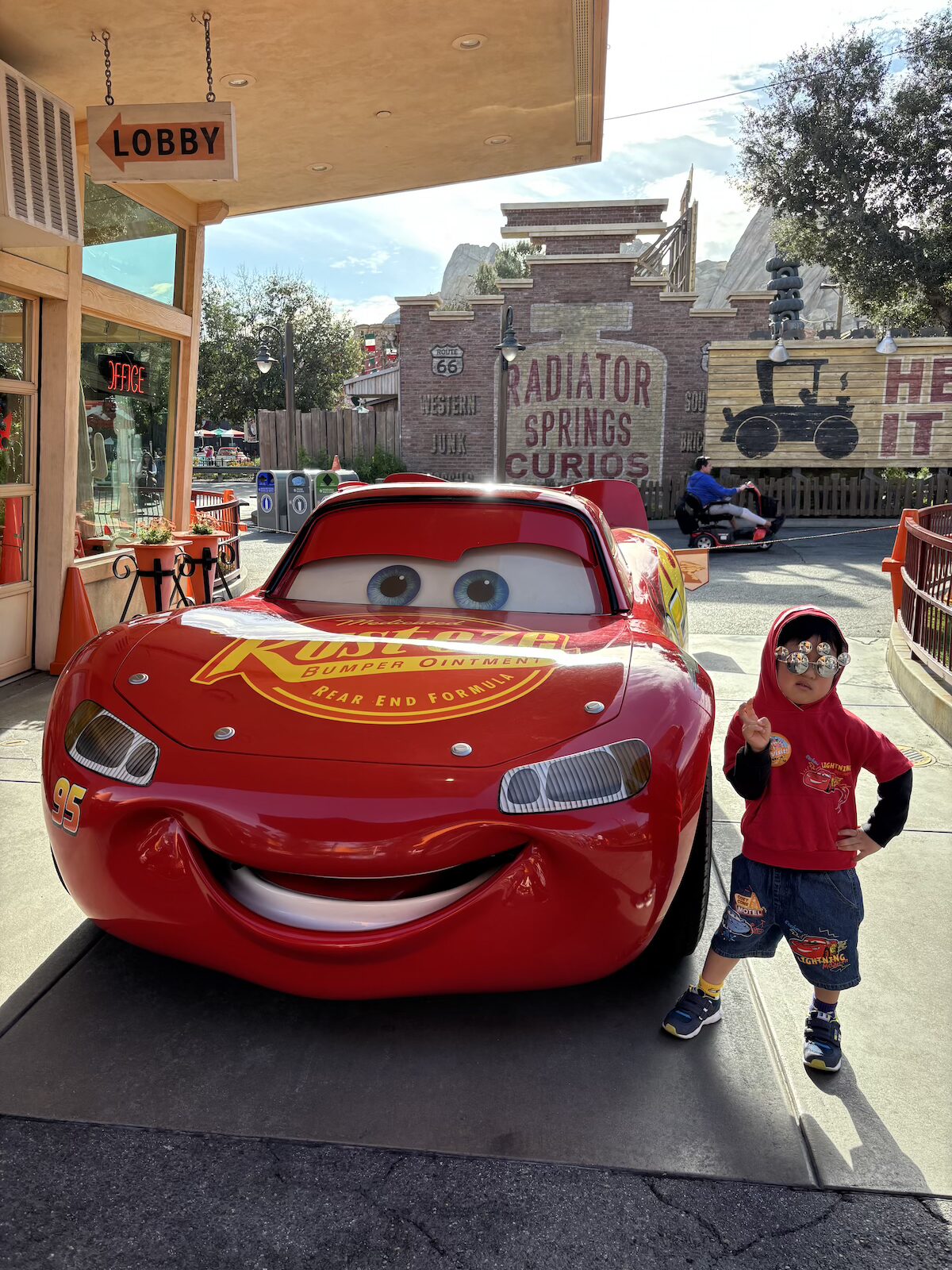 朝のカーズランドでライトニング・マックイーンと写真を撮る4歳の子ども