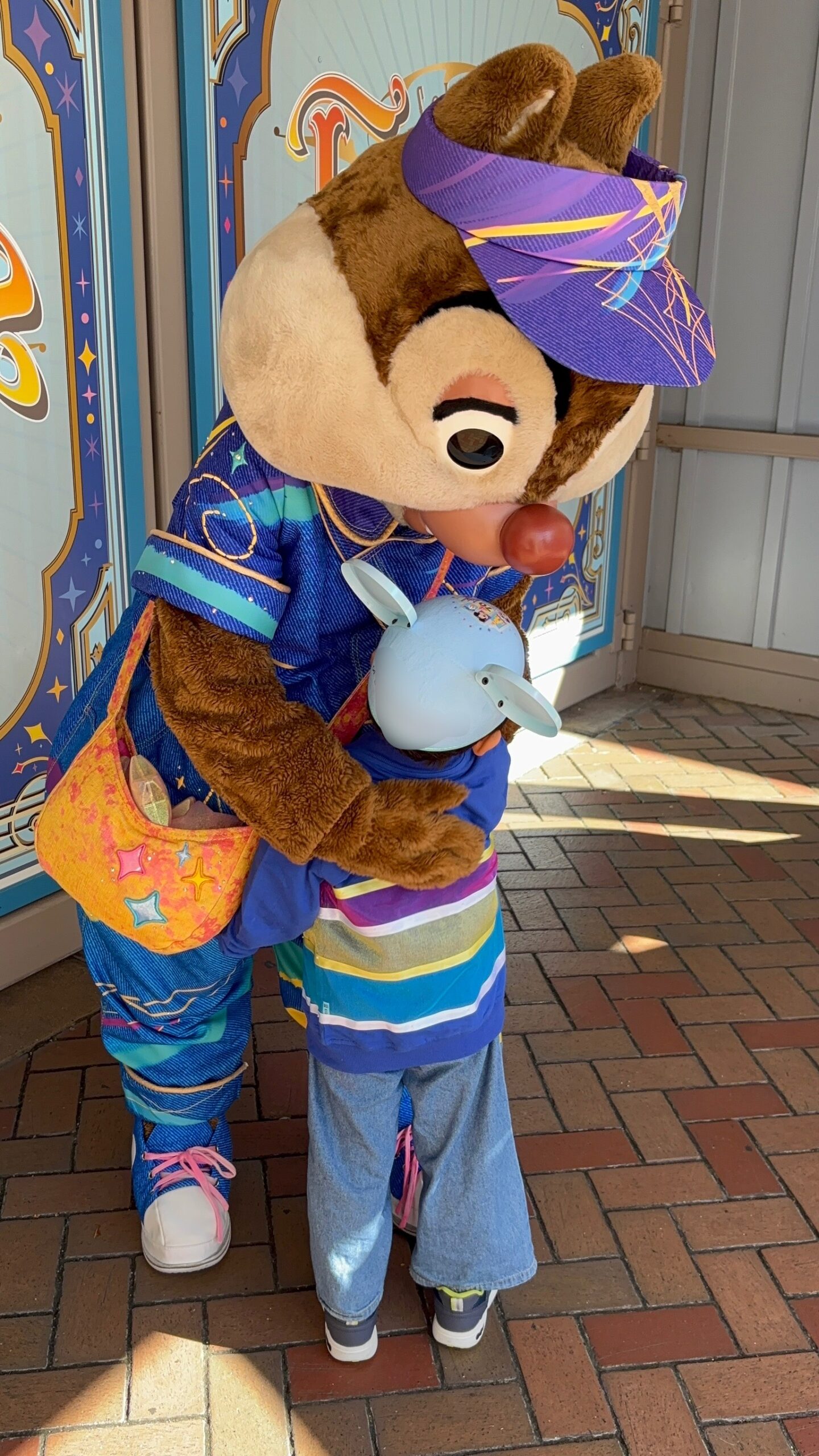 アナハイムディズニー70周年でデールと息子がハグしているグリーティング写真。デールのショルダーバッグに星のデザインが入っている。