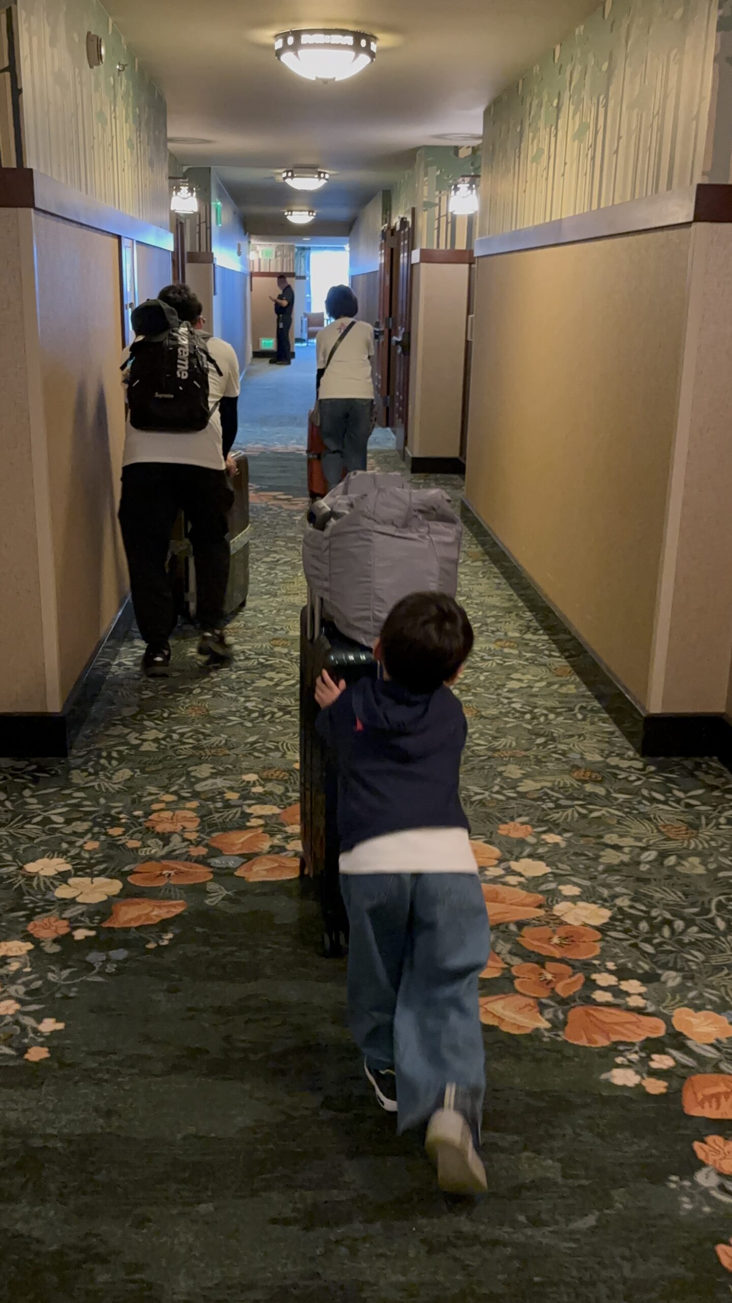 グランドカリフォルニアンホテルの廊下でチェックアウトに向かい、荷物を押して歩く子連れ家族の様子