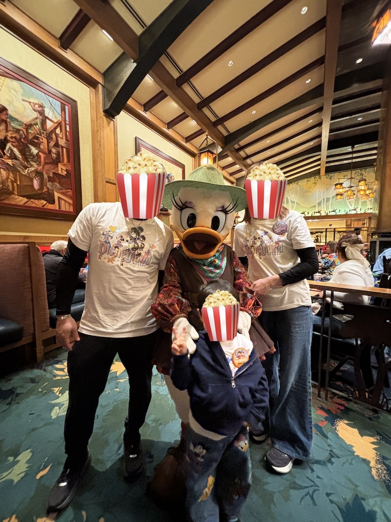 ストーリーテラーズカフェの店内でデイジーダックと家族3人でグリーティングしている写真