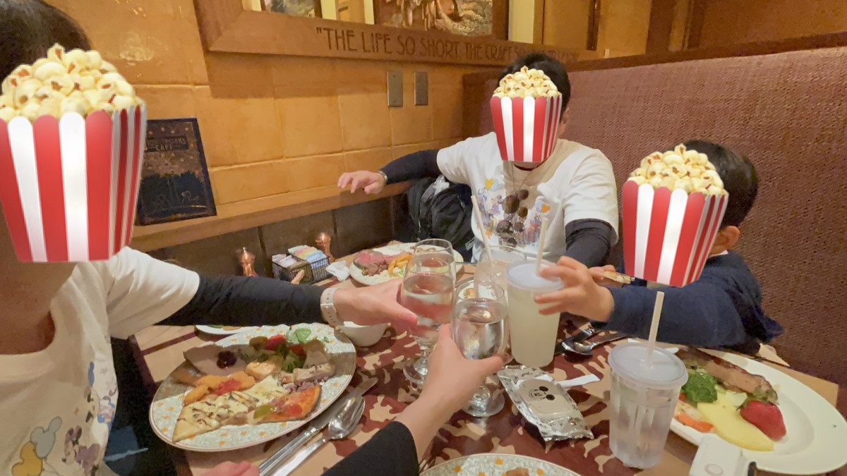 ストーリーテラーズカフェで家族みんなで乾杯している様子。テーブルに料理や子どものお皿も並んでいる