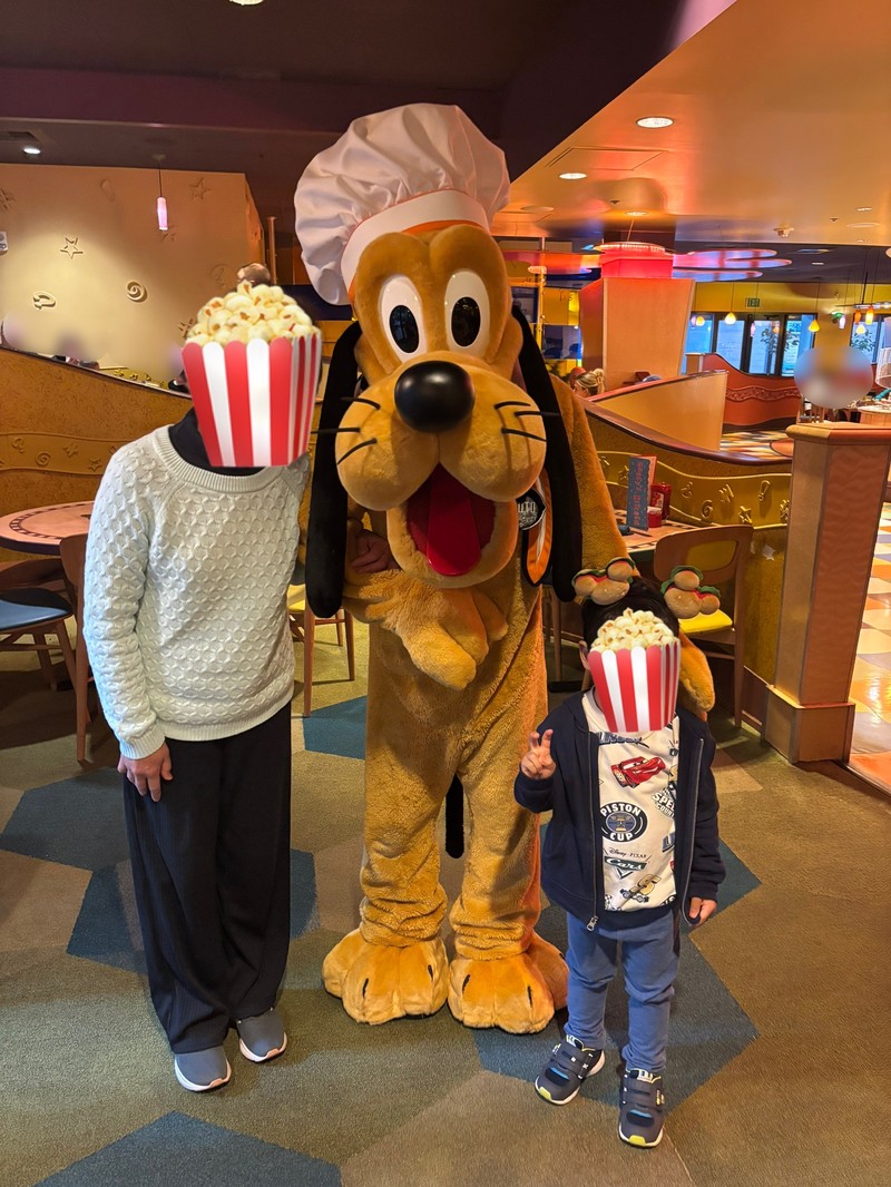 グーフィーズキッチンでフライパン型のネームタグをつけたプルートと息子と祖母のグリーティング写真