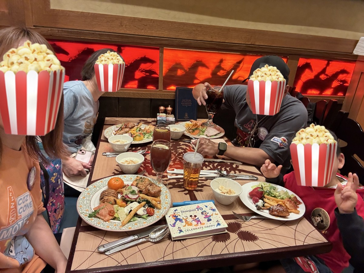 ストーリーテラーズカフェのテーブルで料理と飲み物が並んだ状態で家族みんなでセルフィーを撮っている写真