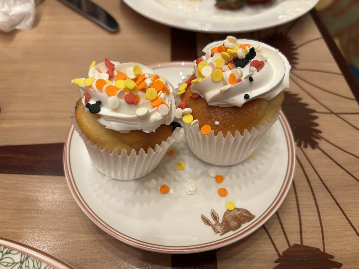 ストーリーテラーズカフェでハッピーエバーアフターの缶バッジを見たキャストがお祝いに持ってきてくれたミッキーシェイプの砂糖フレークが乗ったカップケーキの写真