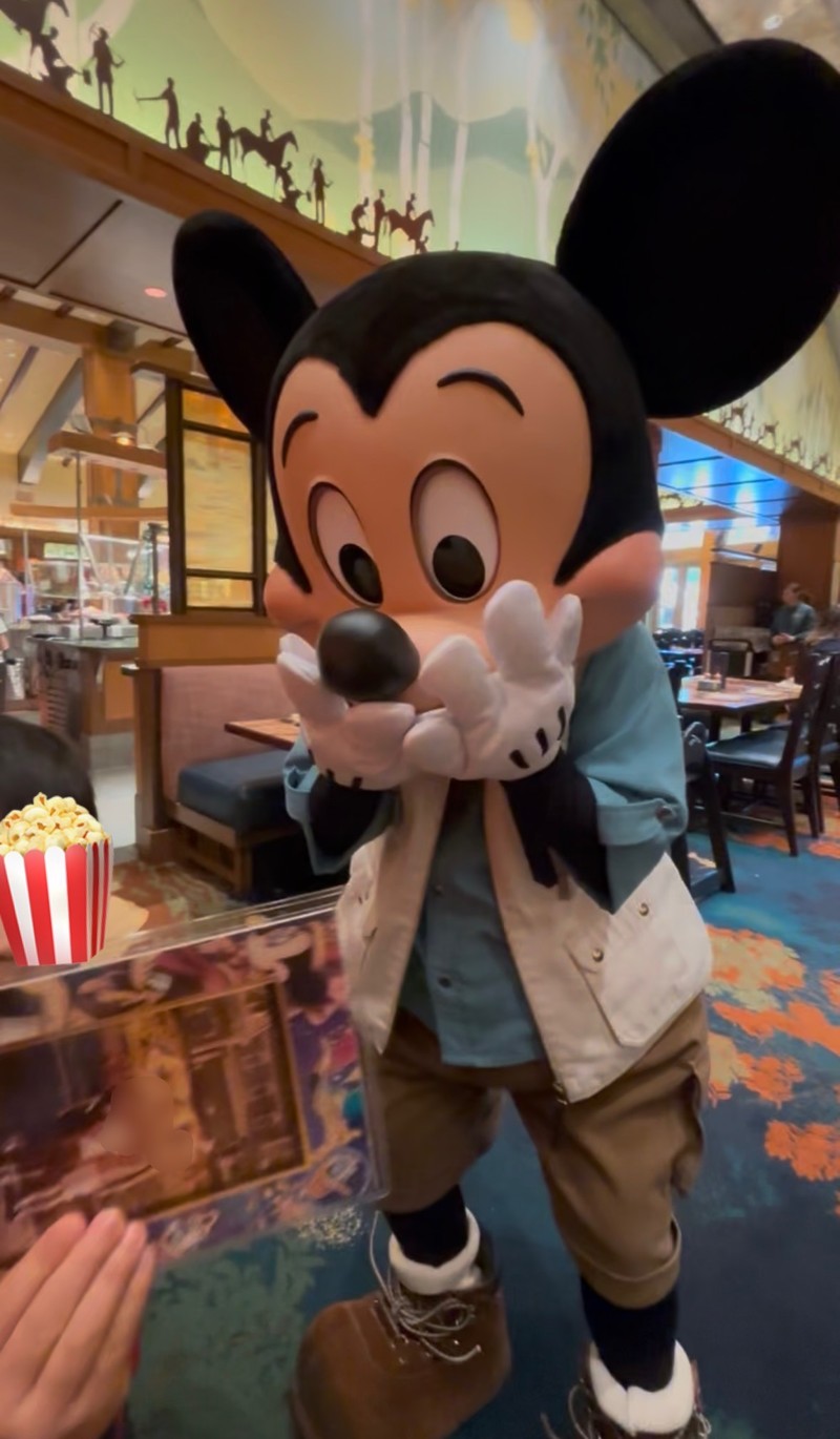 ストーリーテラーズカフェで60周年ディズニーランドの思い出の写真を見てびっくりしているミッキーマウスの写真