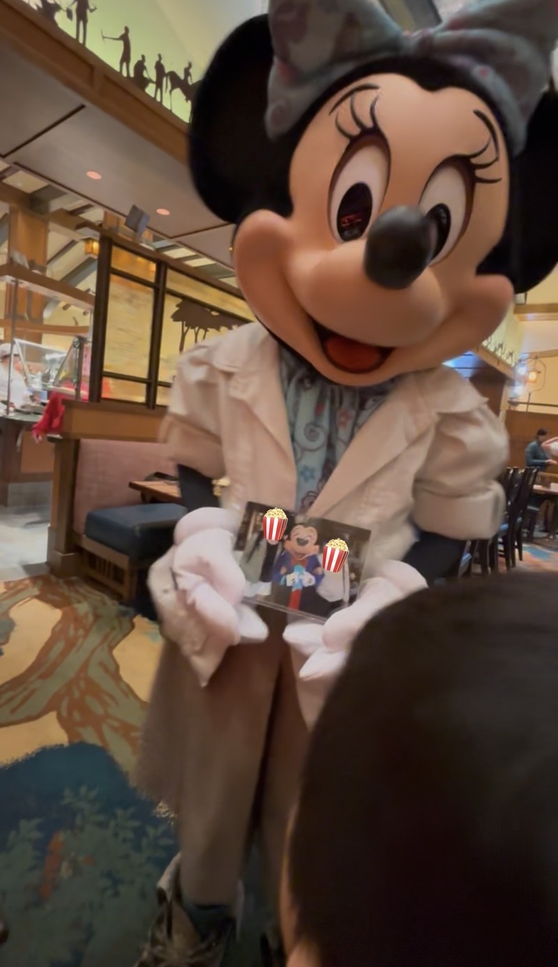 ストーリーテラーズカフェでミニーマウスに60周年ディズニーランドの思い出の写真を見せている様子。ミッキーが写っていた写真を見てミニーが喜んでくれている