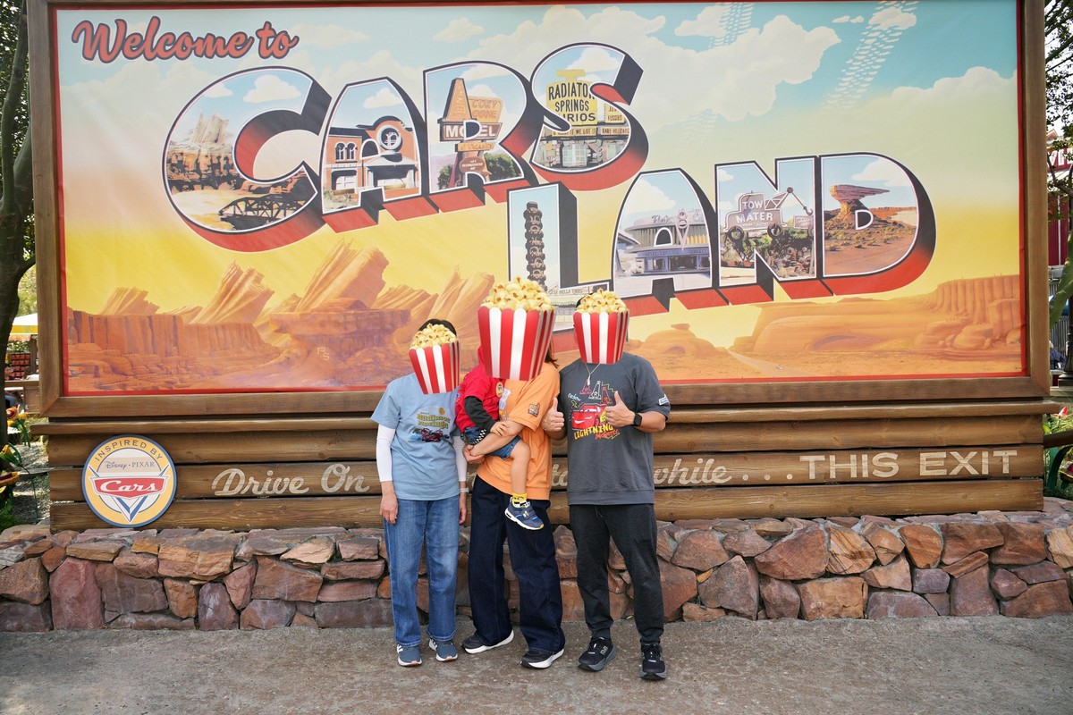カリフォルニアアドベンチャーのカーズランド入口のWelcome to Cars Landの看板前でフォトパスカメラマンに撮影してもらった家族写真